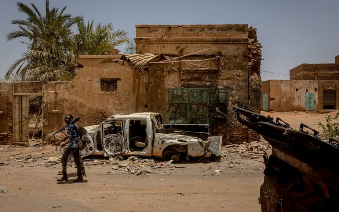 Sudanese Armed Forces soldiers walk through a road lined with destroyed buildings in Al-Shaabi market, liberated from RSF control in March 2024.