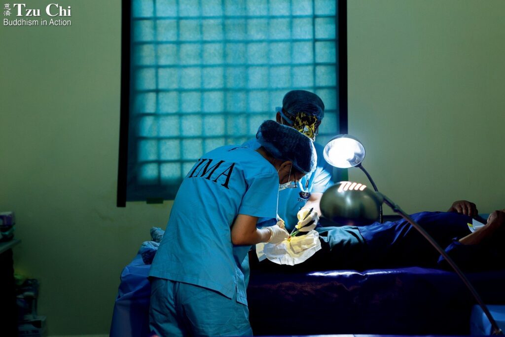 A surgeon taking part in a Tzu Chi free clinic held in Cambodia this past May operates on a patient to remove a tumor. Instead of a disposable surgical drape, white sterile wrapping paper from a surgical glove box was used—an environmentally conscious choice that reflects Tzu Chi's values.